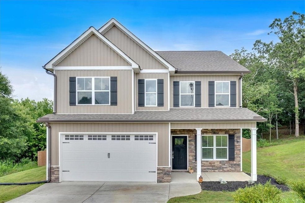 Craftsman-style home with stone siding, a shingled roof, a front yard, and an attached garage