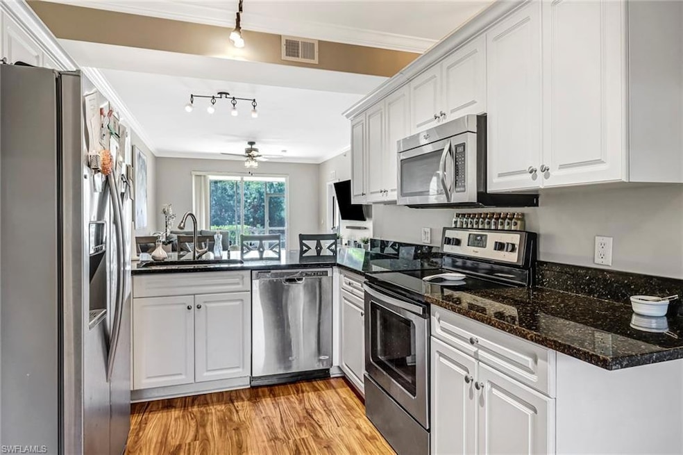 Kitchen with ceiling fan, track lighting, white cabinetry, and appliances with stainless steel finishes