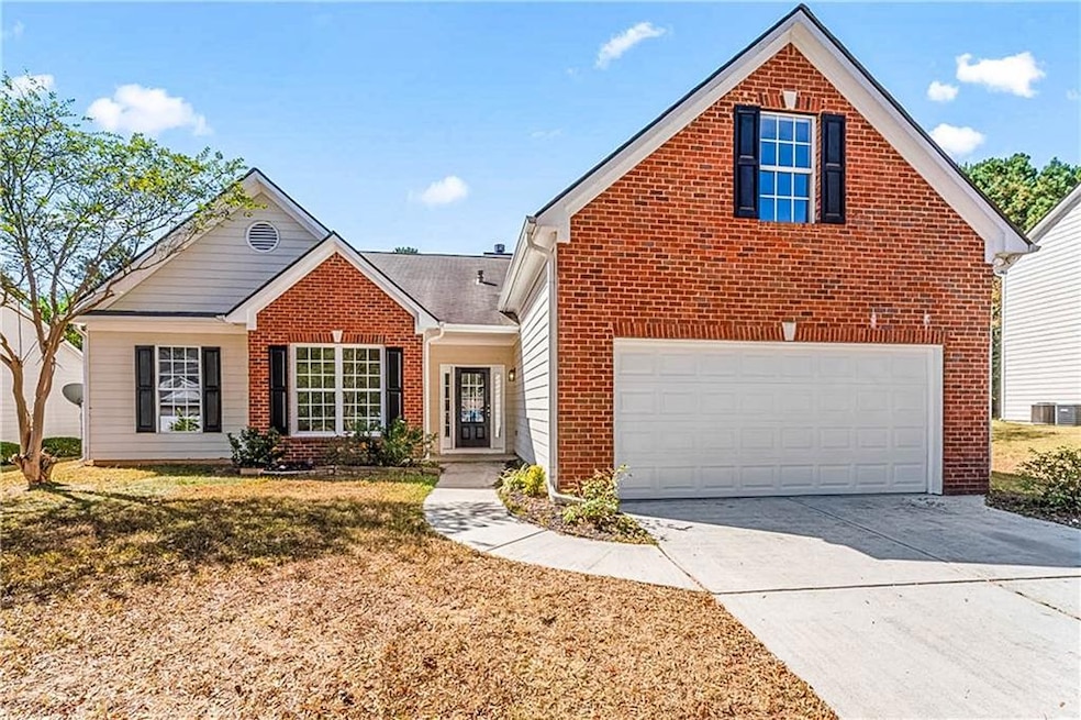 Traditional-style home featuring brick siding, concrete driveway, and a front lawn