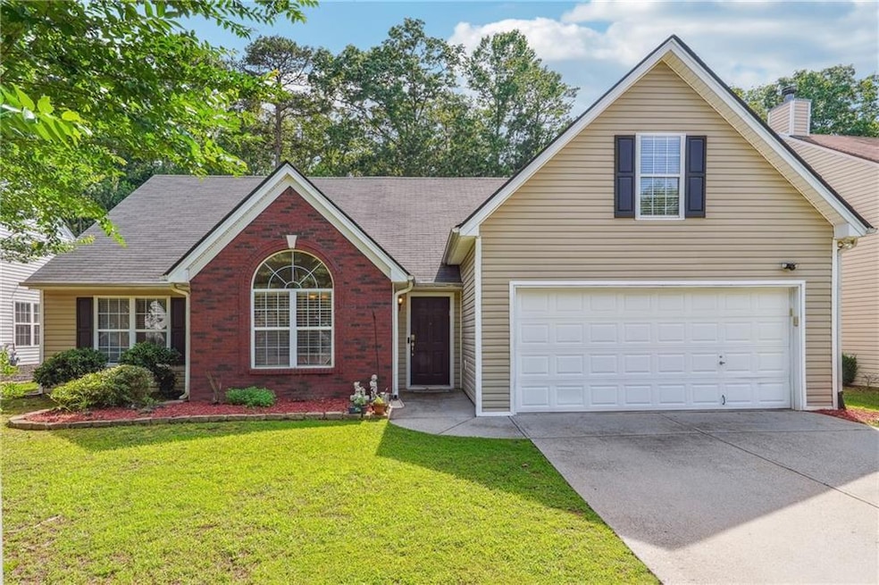 View of front of home with driveway, brick siding, a front yard, a garage, and a chimney