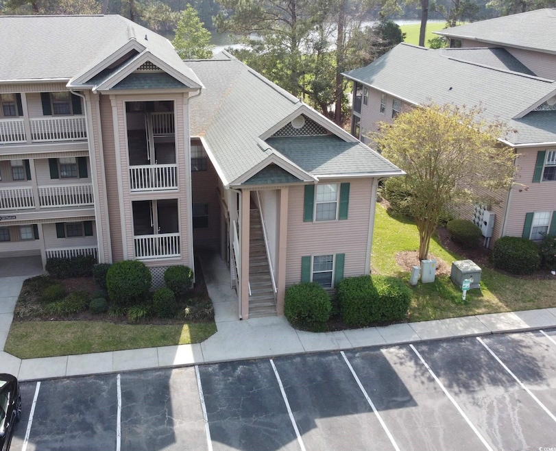 View of property with stairs and uncovered parking