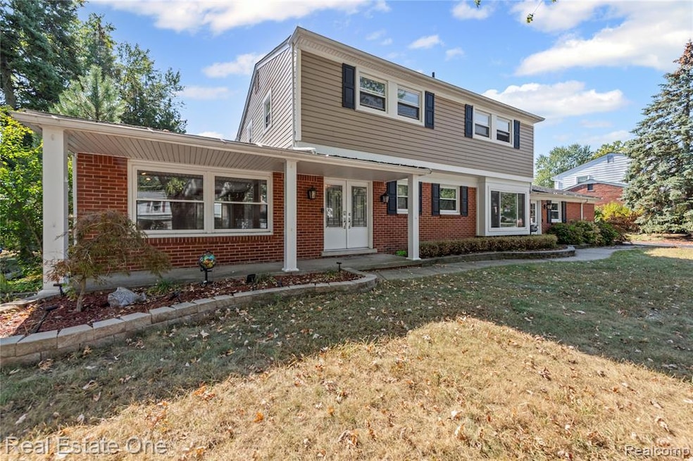 View of front of property featuring a porch, brick siding, a front lawn, and french doors