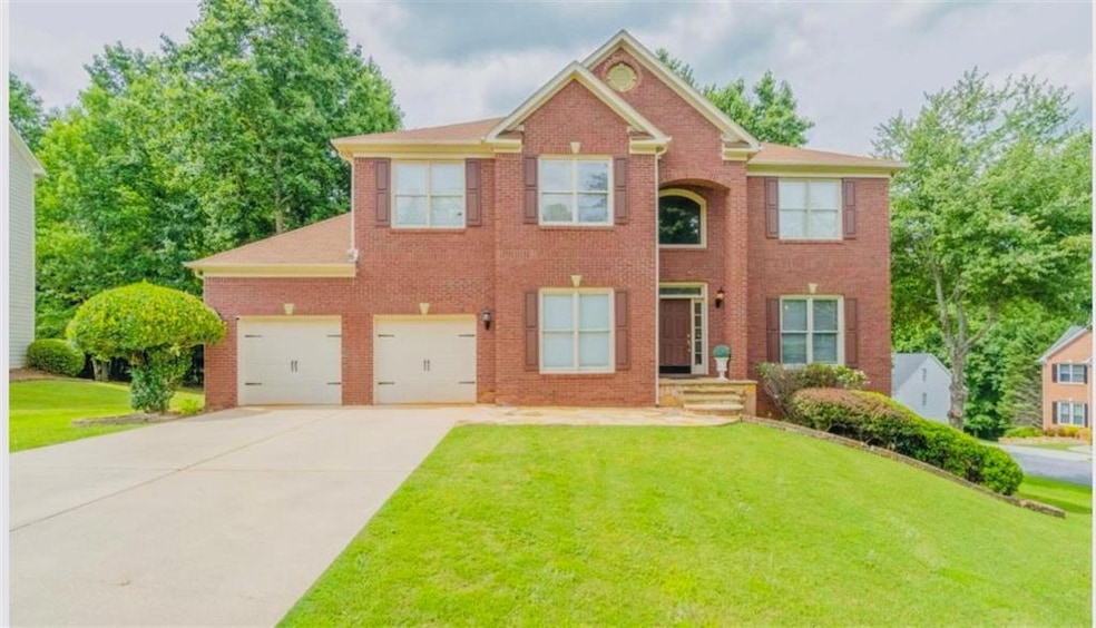 Colonial house with driveway, a front lawn, brick siding, and an attached garage