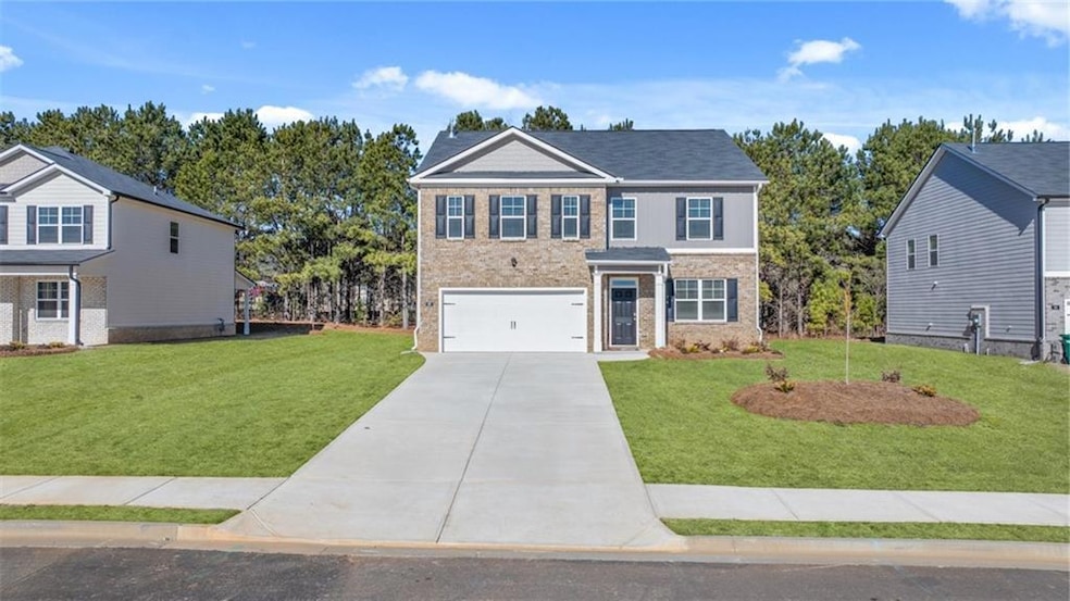 View of front of property featuring driveway, a front yard, a garage, and brick siding