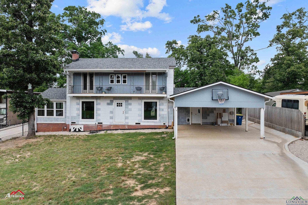 Colonial inspired home featuring a balcony, a chimney, a front lawn, driveway, and fence