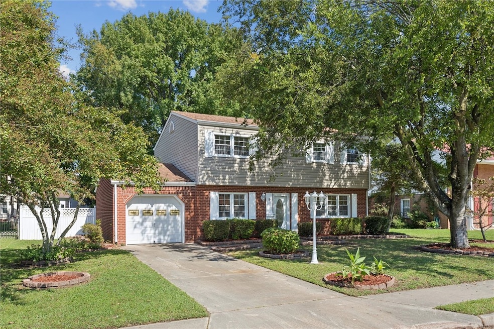 Colonial home featuring a garage, concrete driveway, and brick siding