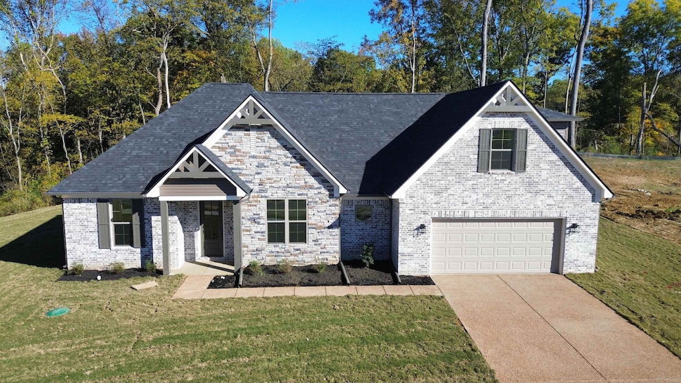 View of front facade featuring a front lawn, driveway, a garage, and brick siding