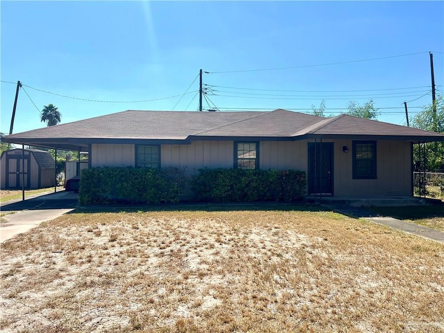 Single story home featuring a carport, a shed, driveway, board and batten siding, and a front lawn