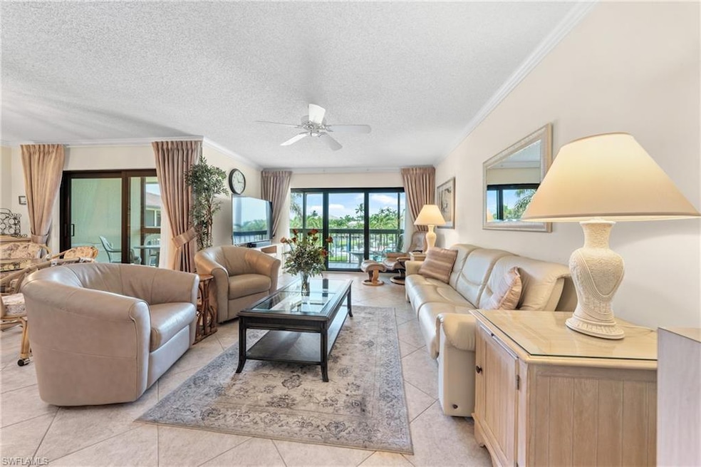 Living room featuring a ceiling fan, crown molding, light tile patterned floors, and a textured ceiling