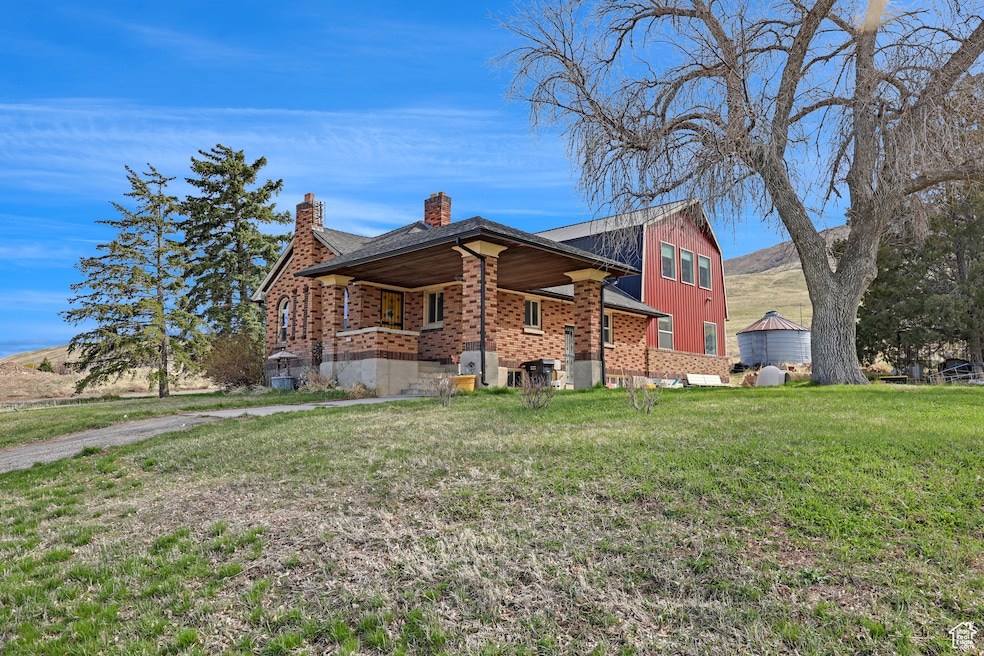 View of front of property featuring a front yard, a chimney, brick siding, board and batten siding, and a porch
