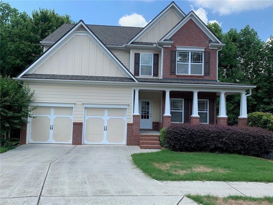 Craftsman house with board and batten siding, brick siding, concrete driveway, covered porch, and a shingled roof