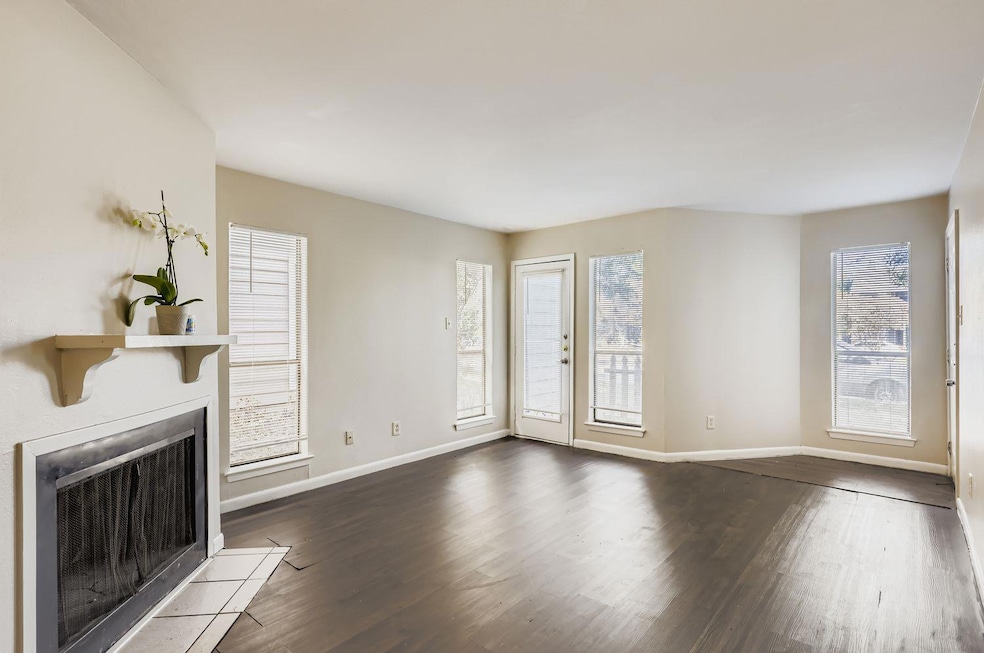 Unfurnished living room with dark wood-style flooring, healthy amount of natural light, and a fireplace with flush hearth