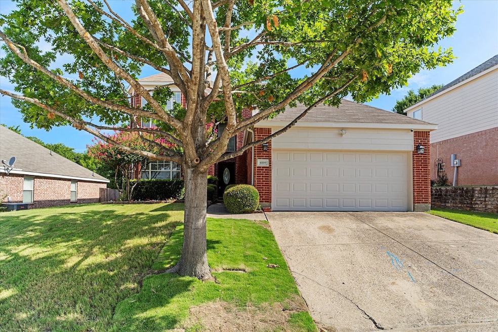 View of front of home with concrete driveway, a front yard, an attached garage, and brick siding