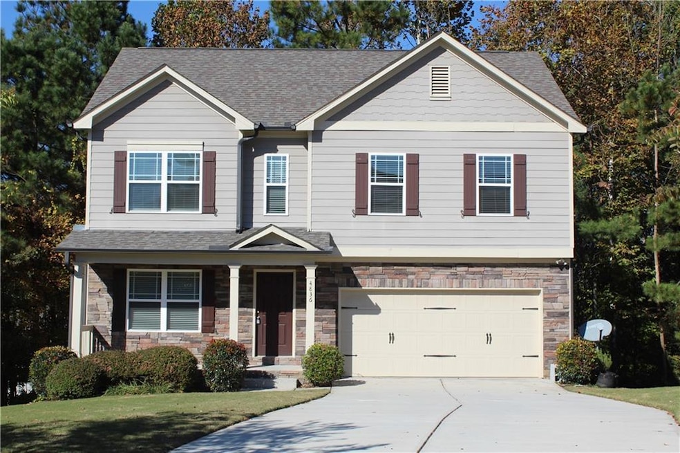 Craftsman-style home with stone siding, covered porch, concrete driveway, and roof with shingles