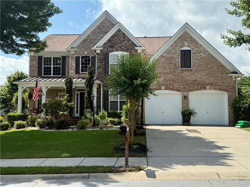 Traditional home featuring a front yard, driveway, a garage, brick siding, and a standing seam roof