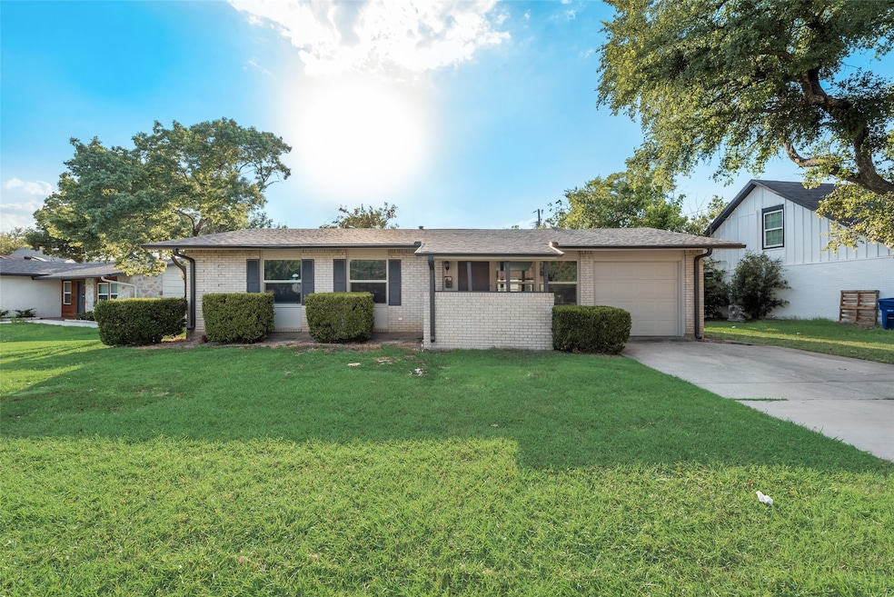 Single story home featuring a front lawn, driveway, a garage, brick siding, and roof with shingles