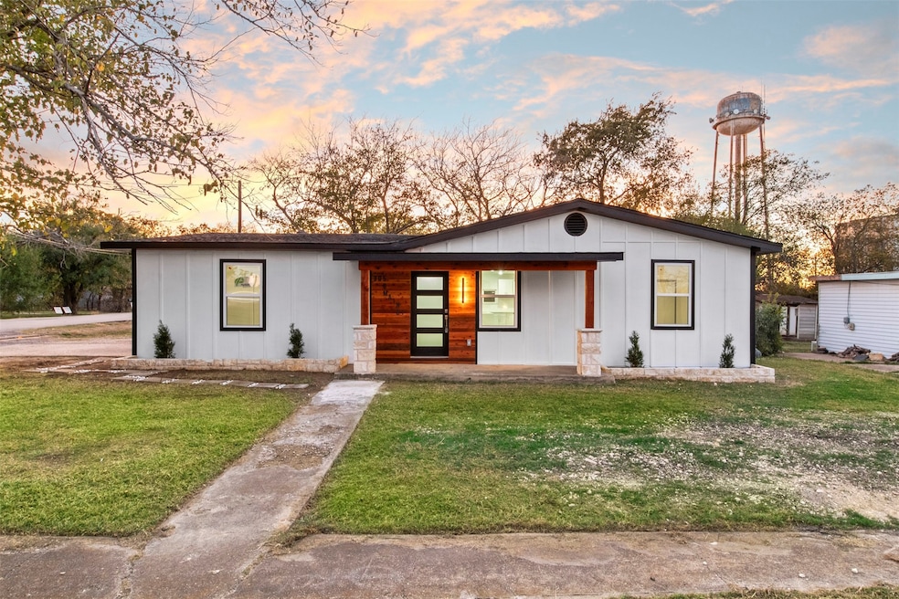 View of front facade with a porch, board and batten siding, and a yard