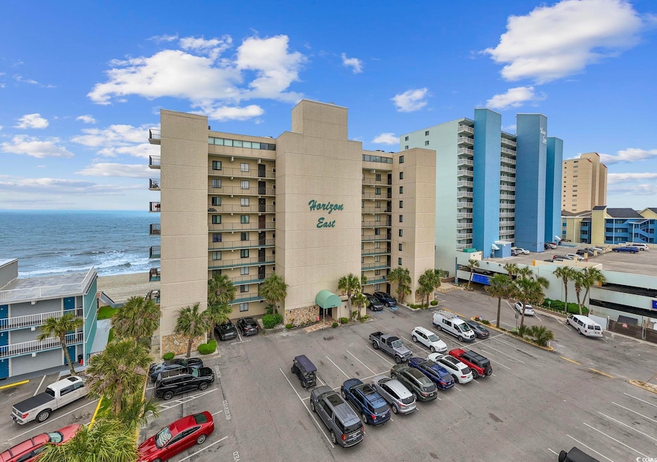 View of apartment building / complex featuring uncovered parking and a water view