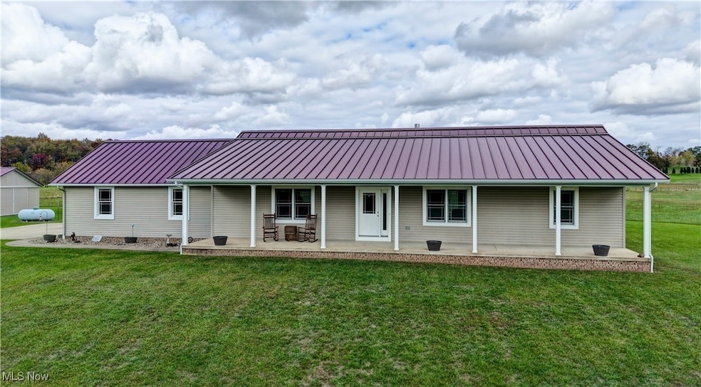 Front view of house with a standing seam roof, a metal roof, and a yard