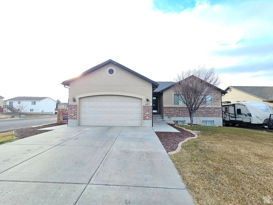 Ranch-style house with a garage, driveway, brick siding, and a front yard