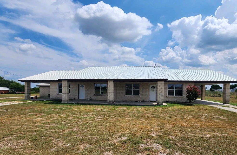 View of front of home with an attached carport, metal roof, a front lawn, and concrete driveway