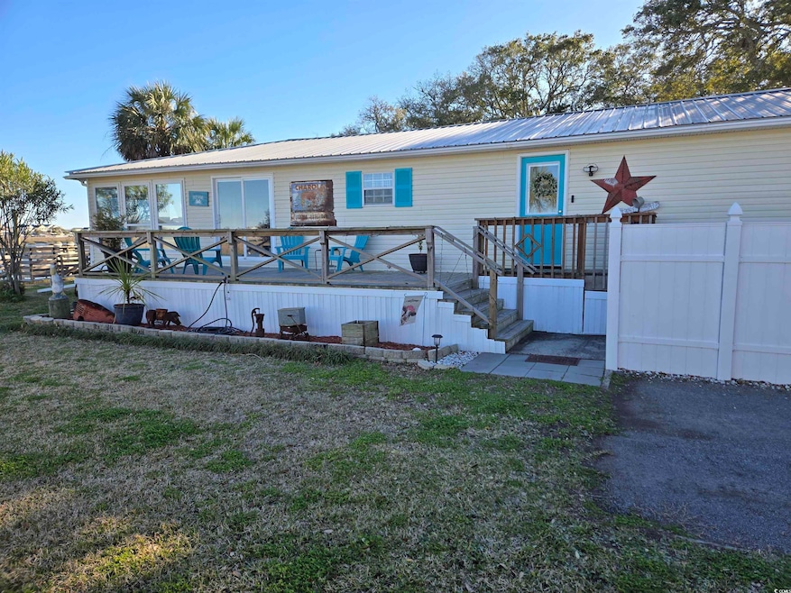 Rear view of property featuring metal roof, a wooden deck, stairway, and a yard