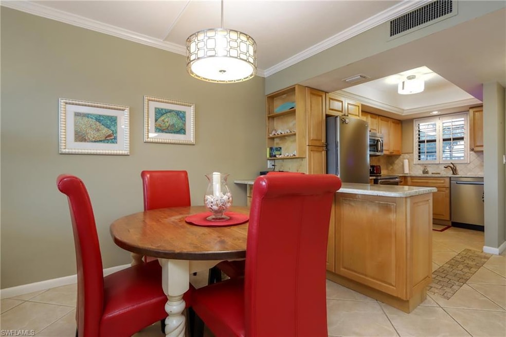 Dining area featuring light tile patterned floors, crown molding, and a raised ceiling