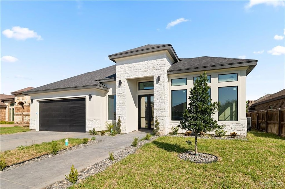 Prairie-style home featuring stone siding, a garage, driveway, and a shingled roof