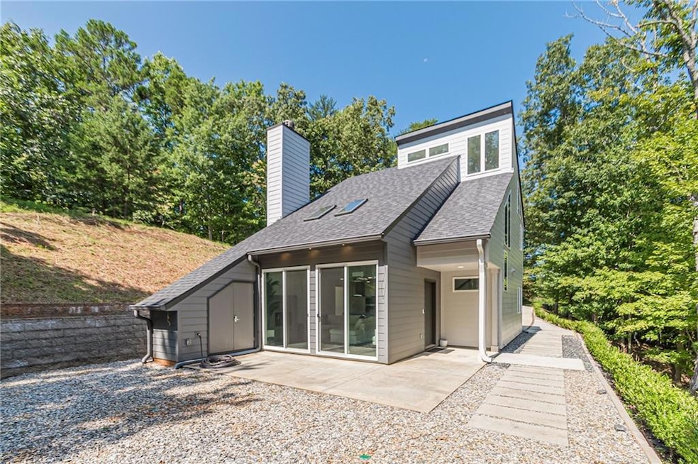 Rear view of house featuring a patio area, a chimney, and roof with shingles