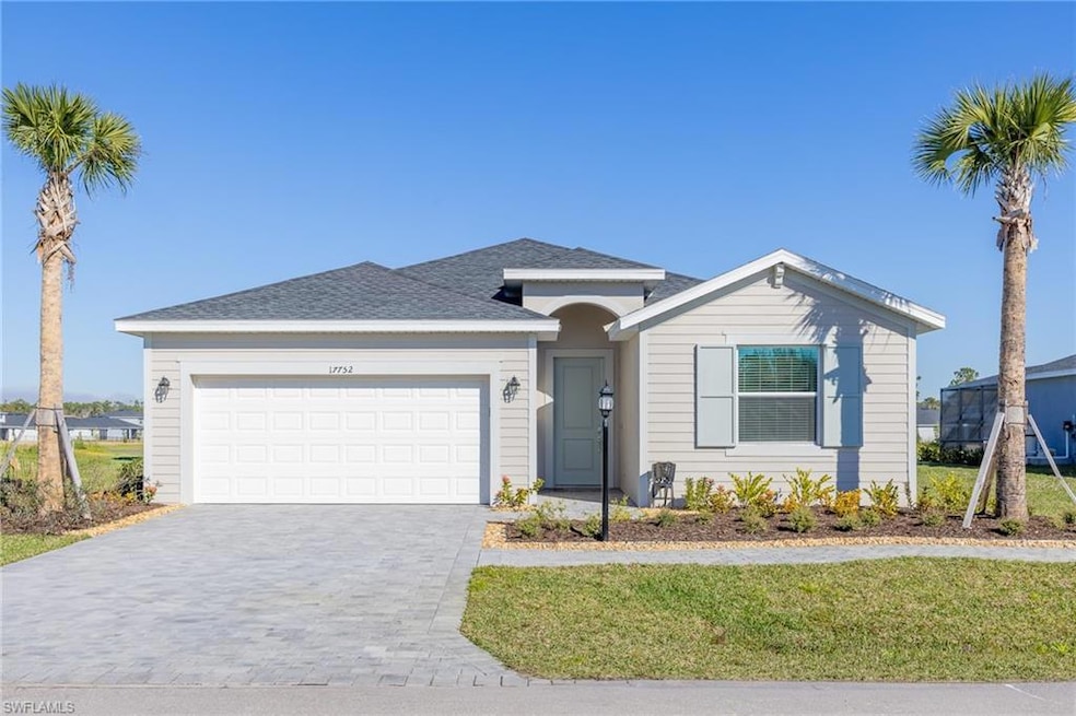 Ranch-style home featuring decorative driveway, an attached garage, a front lawn, and roof with shingles
