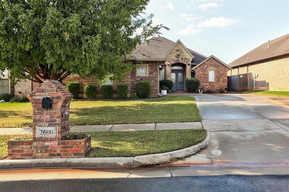 View of front facade with brick siding, driveway, and a shingled roof