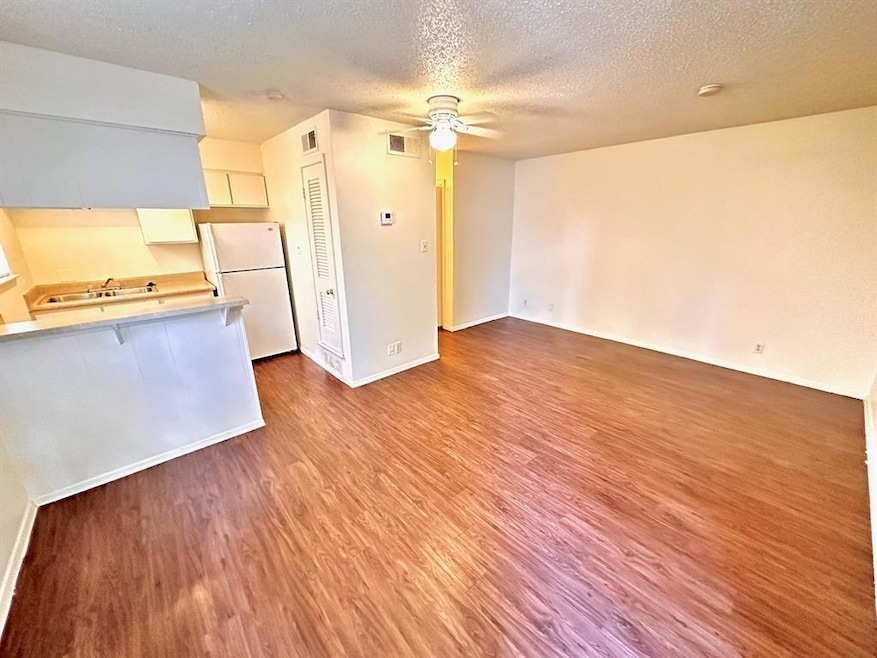 Unfurnished living room featuring dark wood finished floors, a textured ceiling, and a ceiling fan