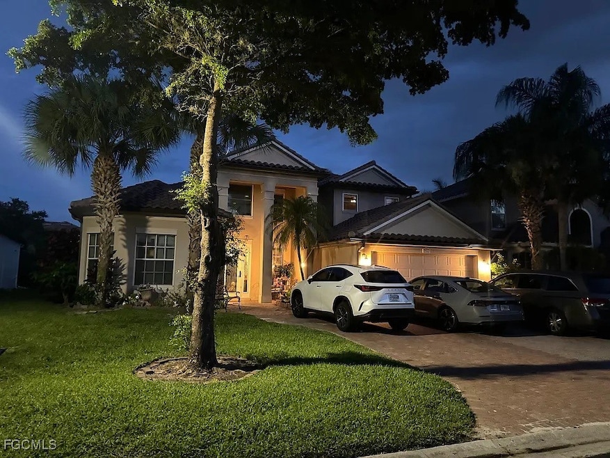 View of front of house featuring driveway, an attached garage, a lawn, and stucco siding