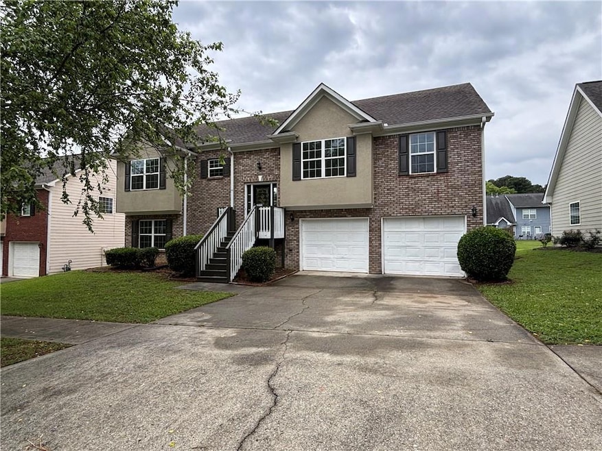 Bi-level home with brick siding, a garage, a front yard, and concrete driveway