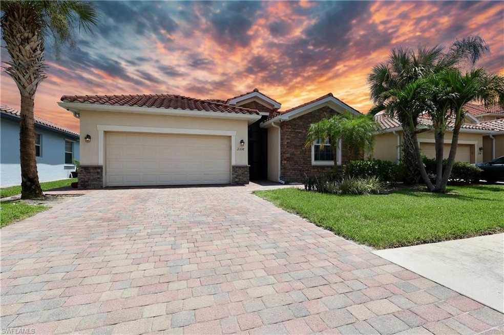 View of front of home featuring stone siding, stucco siding, decorative driveway, a front yard, and an attached garage