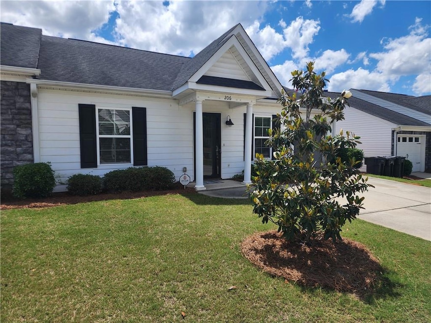 View of front of home with a front yard, concrete driveway, roof with shingles, and an attached garage