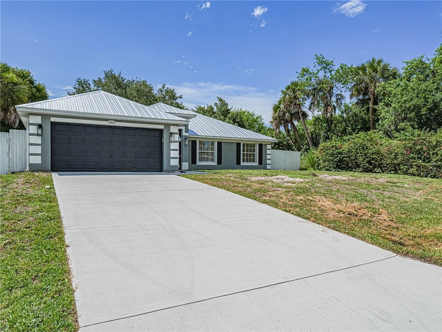 View of front facade with a metal roof, concrete driveway, an attached garage, and stucco siding
