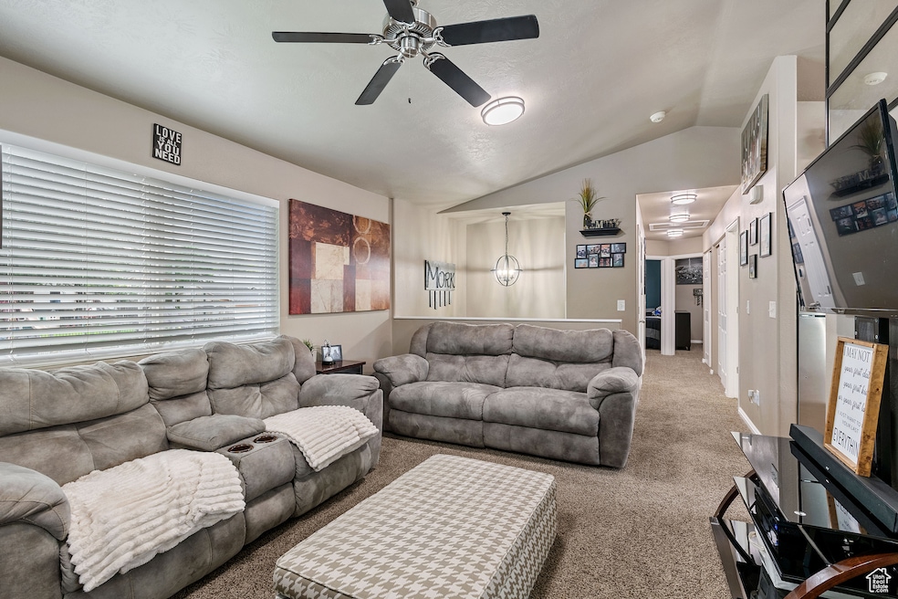 Carpeted living room featuring vaulted ceiling and ceiling fan