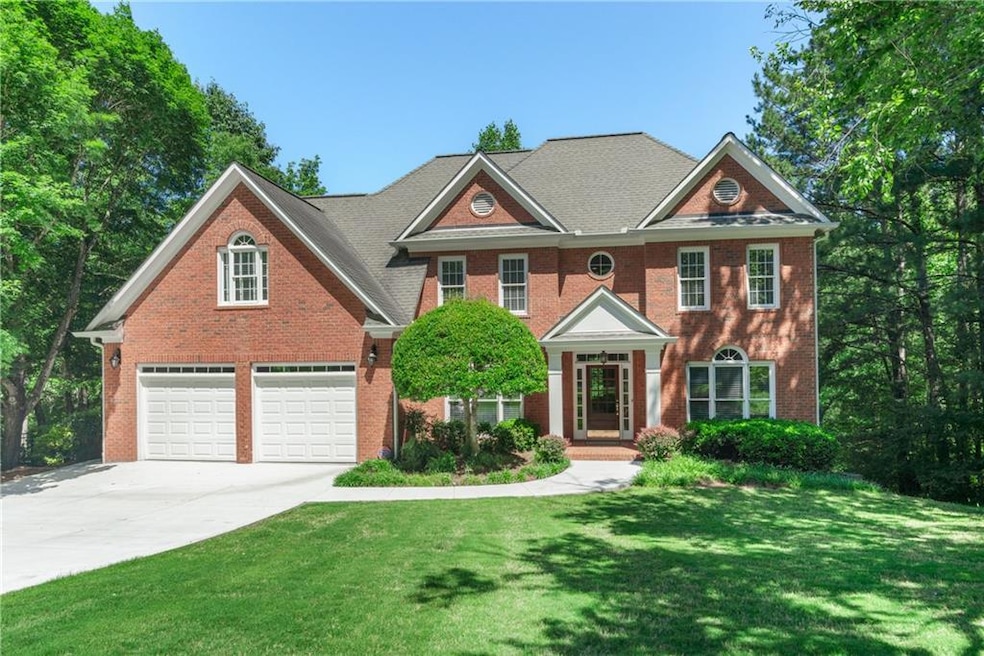 Georgian-style home with driveway, brick siding, a front lawn, and a garage