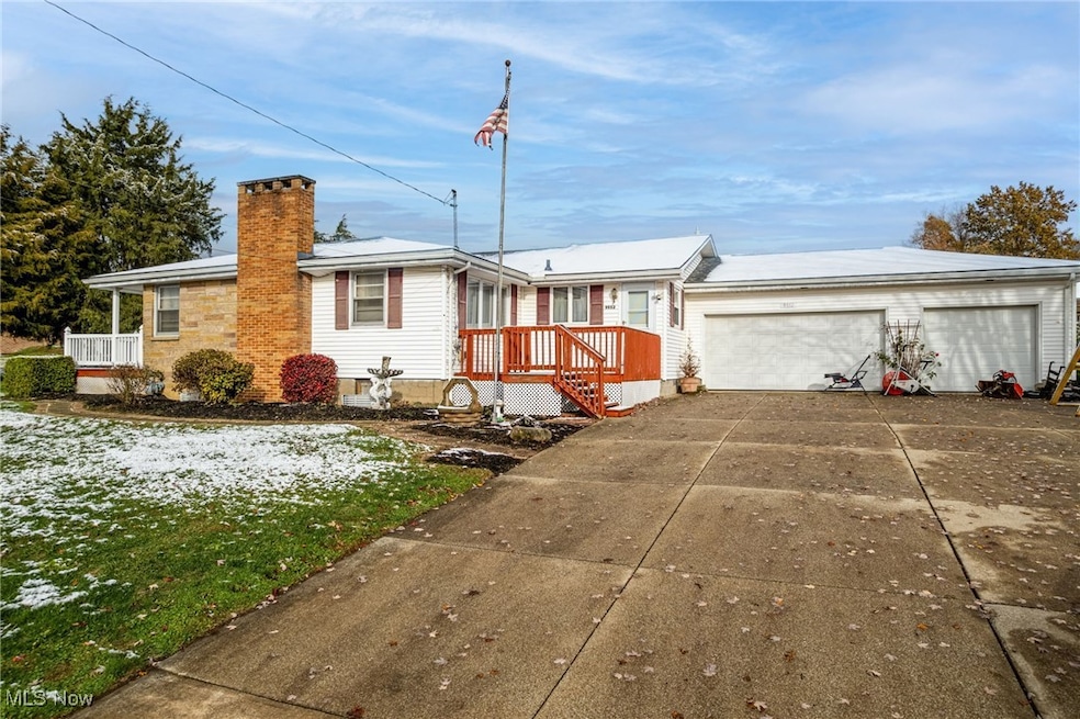 Single story home featuring a chimney, driveway, and an attached garage