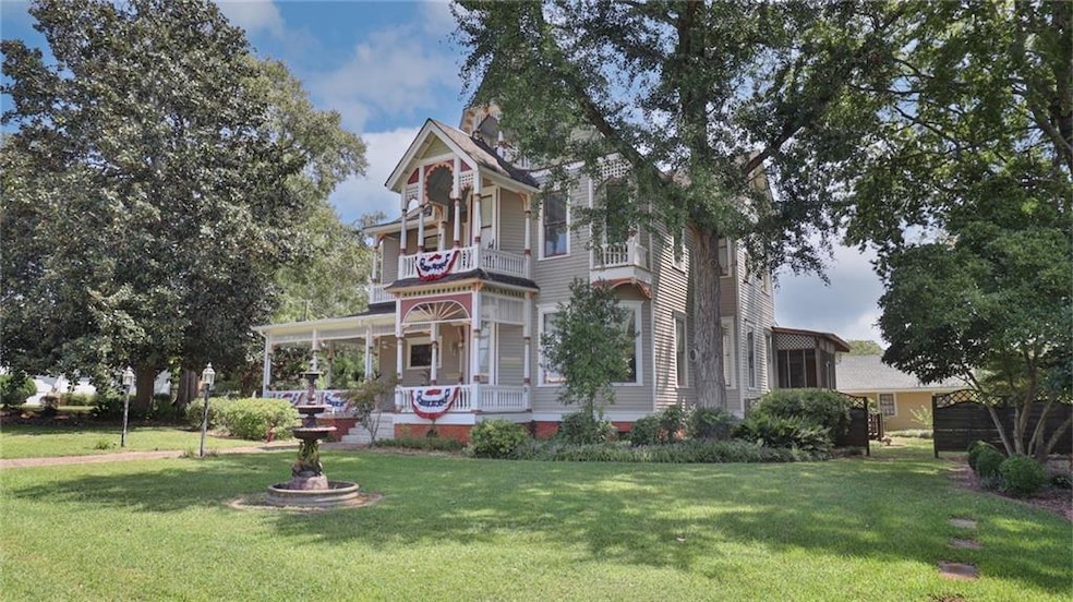 Victorian home with a front yard and a balcony