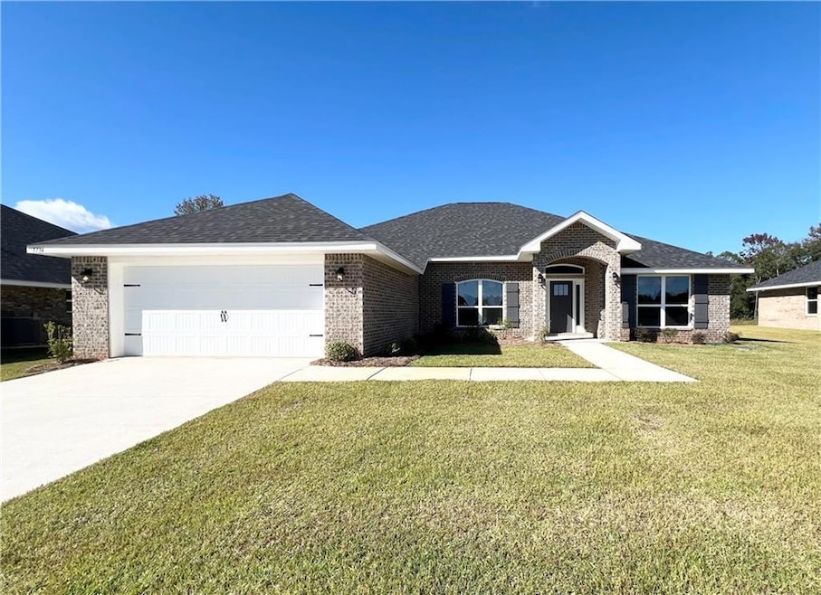View of front of home featuring brick siding, a front lawn, and driveway