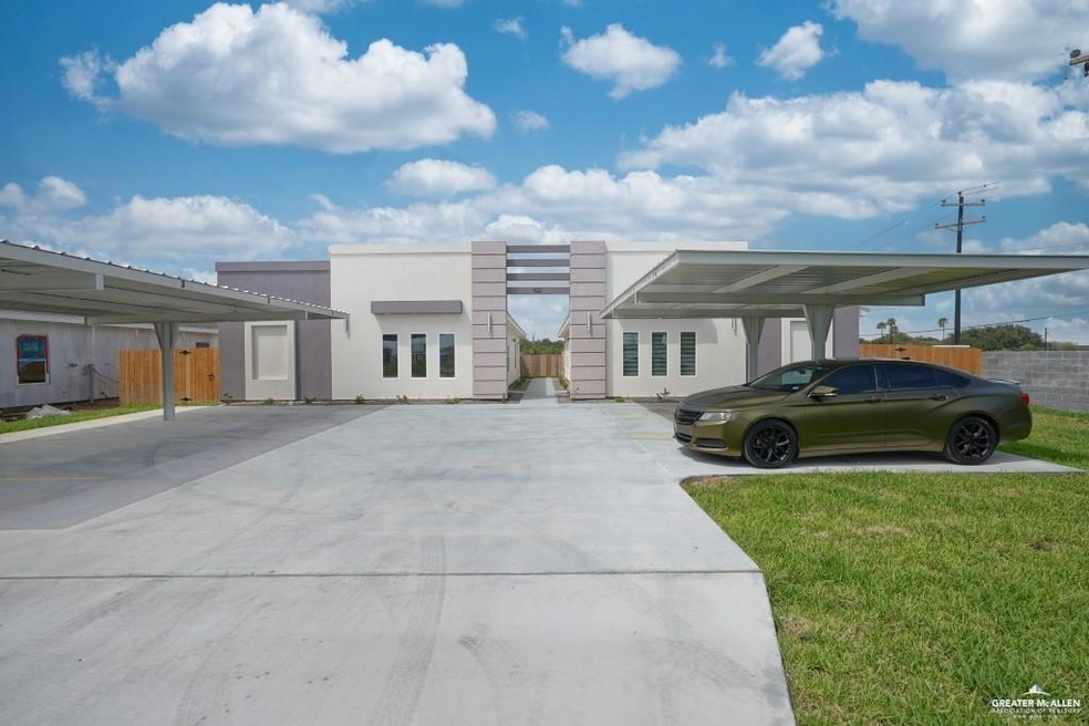 View of front of property featuring covered parking, fence, a front yard, and stucco siding