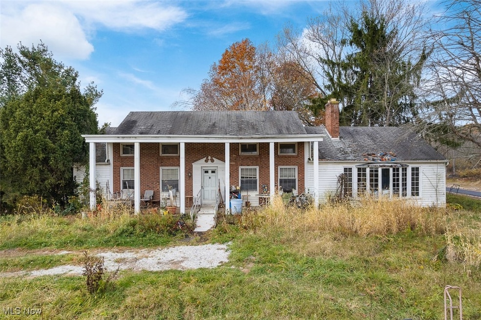 View of front facade featuring a porch, a chimney, and brick siding