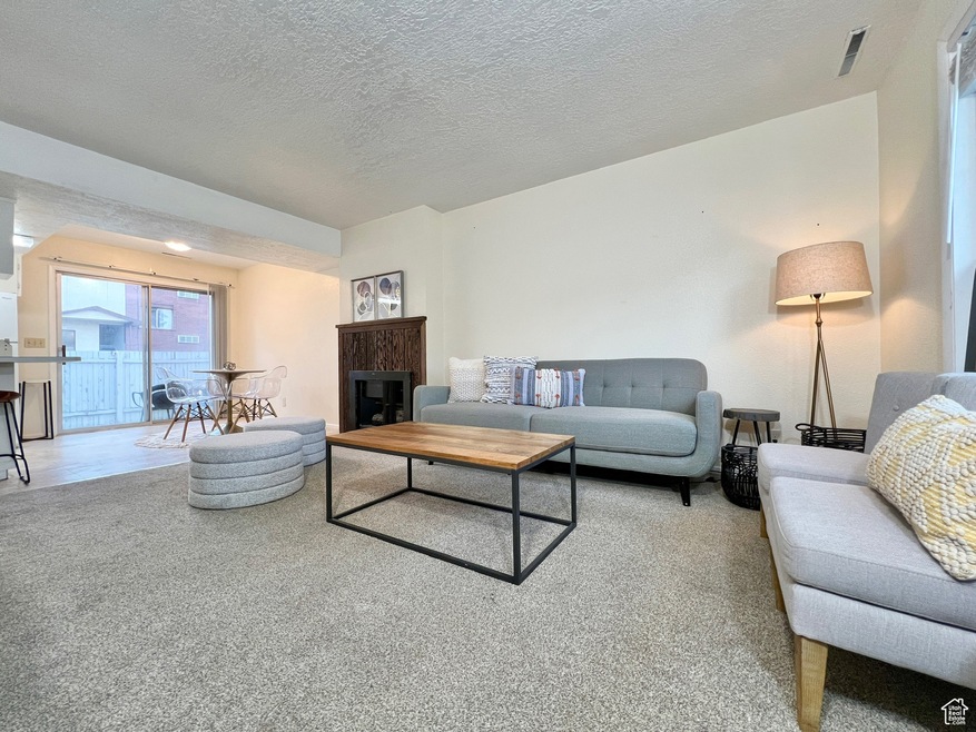 Living room with a textured ceiling, carpet floors, and a fireplace