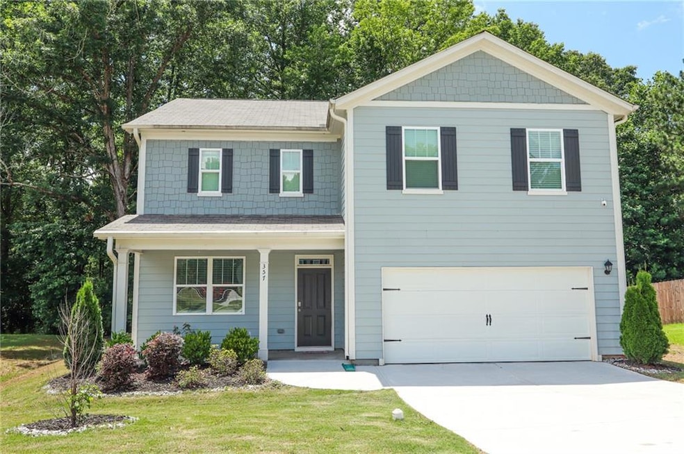 View of front of home with driveway, an attached garage, a front lawn, and covered porch