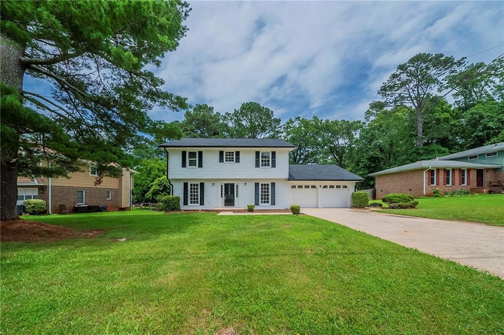 View of front of property featuring a garage, driveway, and a front lawn