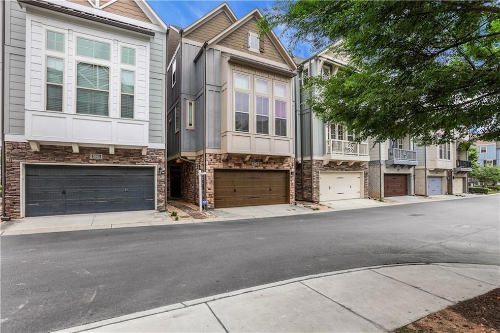 View of property featuring an attached garage, stone siding, and concrete driveway