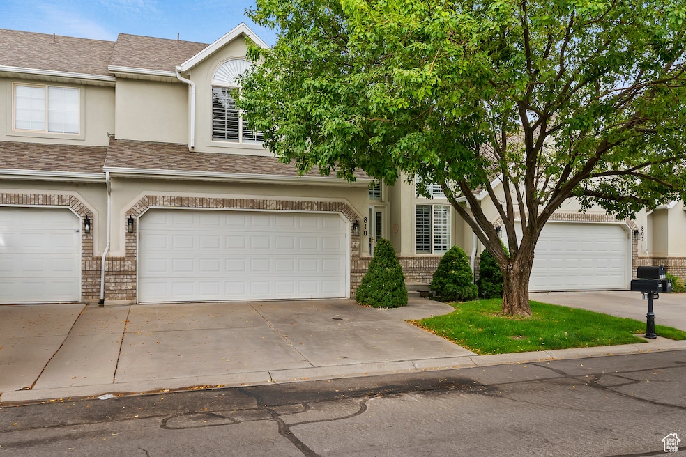Traditional-style home featuring roof with asphalt shingles, concrete driveway, stucco siding, and brick siding