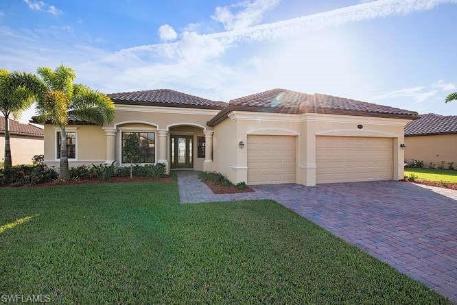 Mediterranean / spanish house featuring decorative driveway, an attached garage, a front lawn, stucco siding, and a tiled roof